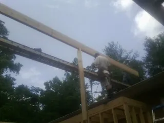 Carpenter setting a ridge beam over a new addition frame — Ice Dam Removal by Roofing Brothers in South Mills