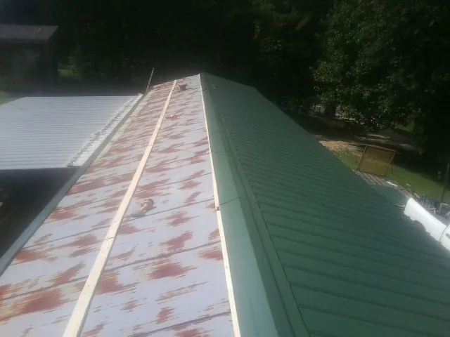 Old rusted panels beside newly installed green metal roofing — Wind Damage Roof Repair by Roofing Brothers in South Mills