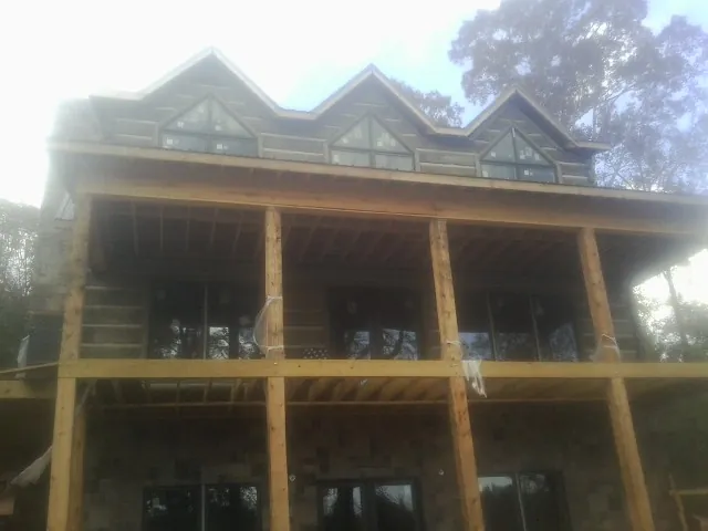 Dormers and porch framing on a large log home under construction — Roof Coating work by our crew in South Mills