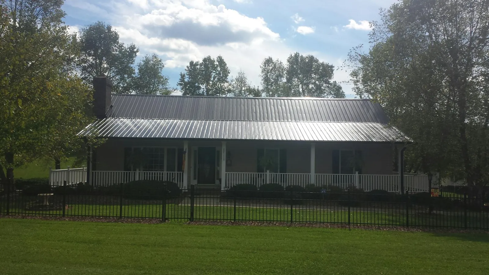 Gray metal roof on a brick ranch with a full width front porch — Gutter Guard Installation work by our crew in South Mills