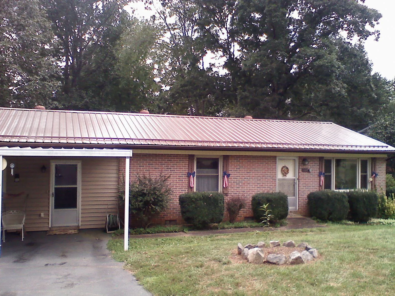 Bronze metal roof and carport on a brick ranch home — Roof Repair work by our crew in South Mills