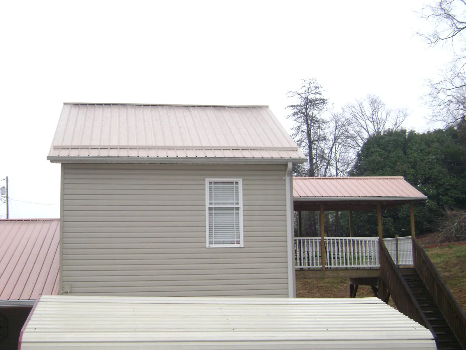 Tan metal roofs on a two story addition and attached porch, from a Roof Replacement job in South Mills