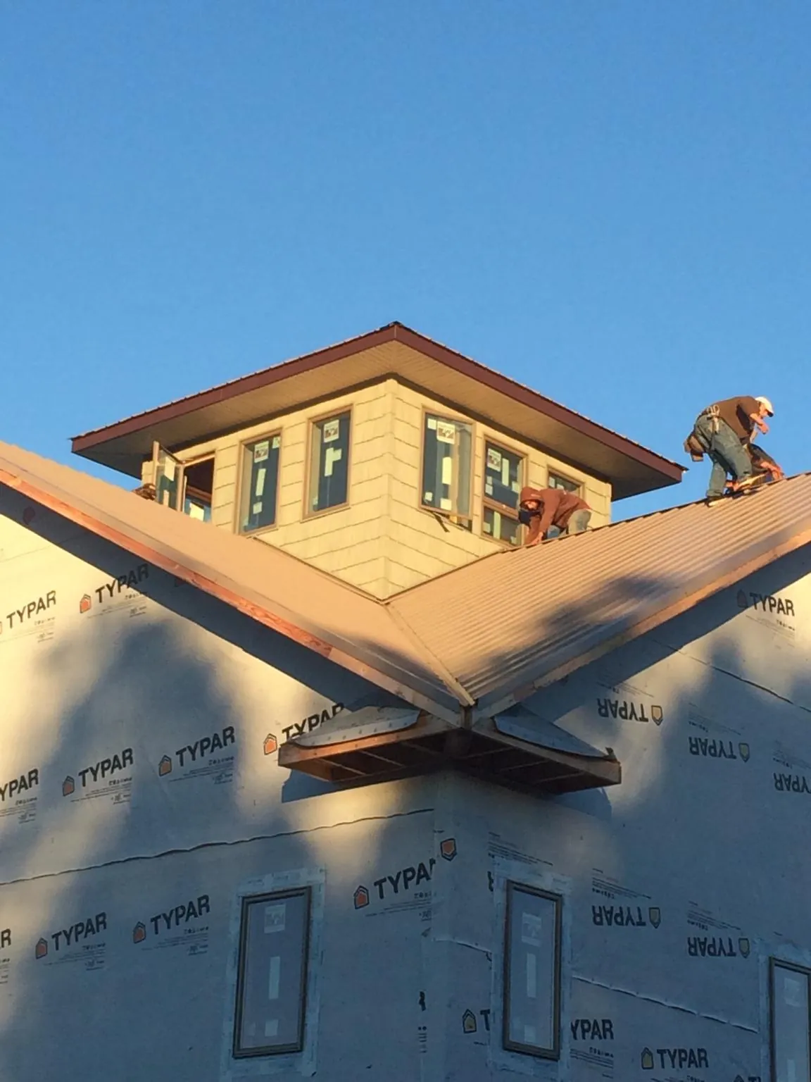 Roofers working around a rooftop cupola on a new metal roof at sunset — Roof Waterproofing in South Mills by Roofing Brothers